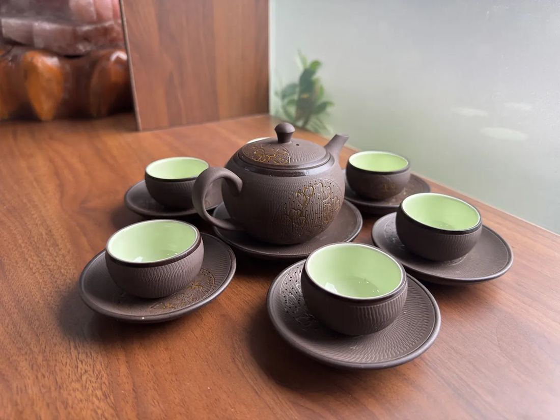 Nhập ấm chén bán kèm trà: sáu bộ Bát Tràng, vốn bỏ ra và lãi thu về trên mỗi bộ Bộ ấm chén đầy đủ bày trên bàn gỗ tiếp khách tại điểm bán