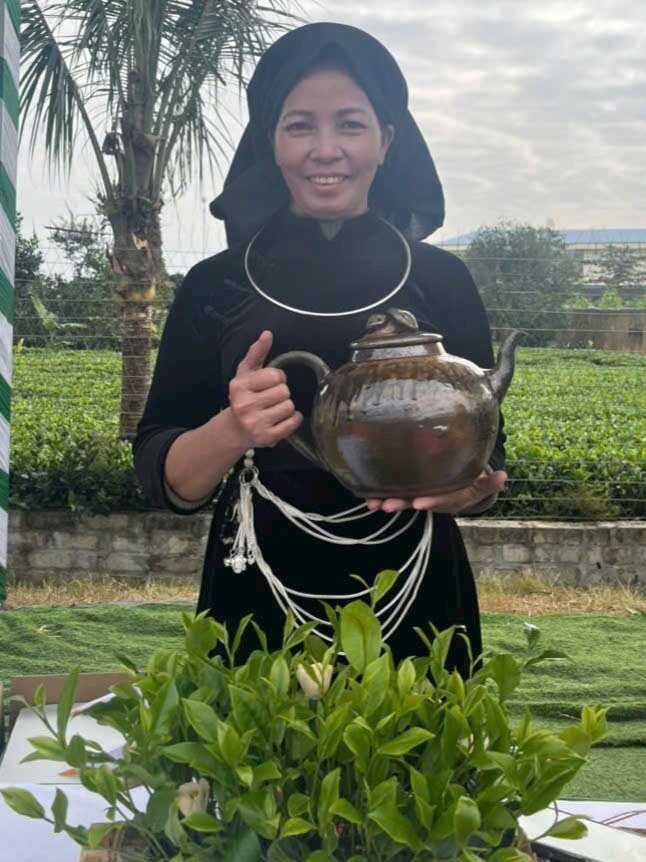 Trải nghiệm vùng chè TRAVINA Nghệ nhân Ma Thị Tuyến của HTX Tâm Trà Việt trong trang phục truyền thống, cầm ấm trà bên vùng chè Đại Từ – La Bằng, Thái Nguyên