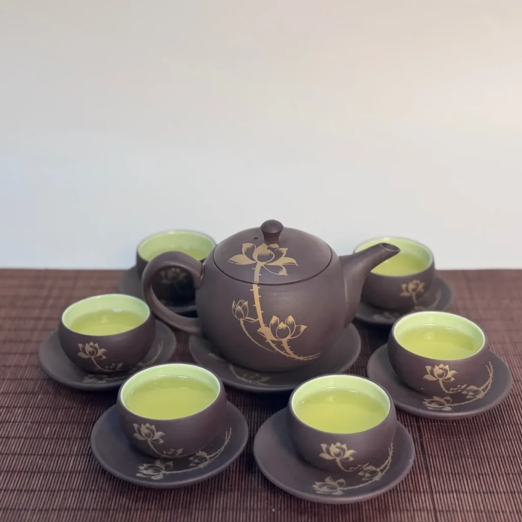 Bộ ấm chén tử sa vẽ sen vàng, chén đã rót trà xanh
