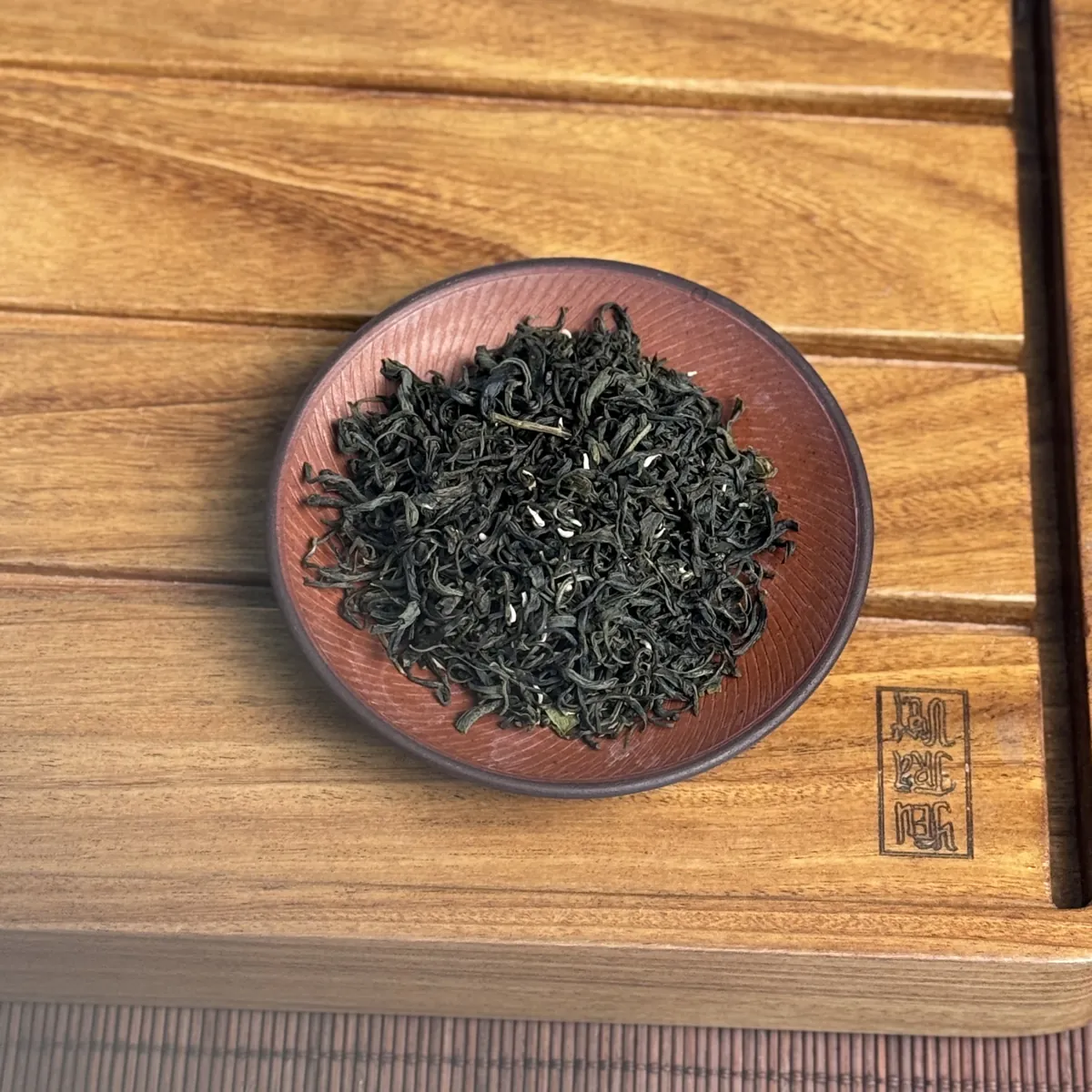 Bã trà và hàng lỗi ở quán: thu gom thế nào, ghi sổ ra sao Cận cảnh đĩa trà xanh khô cánh xoăn trên khay gỗ – TRAVINA HTX Tâm Trà Việt