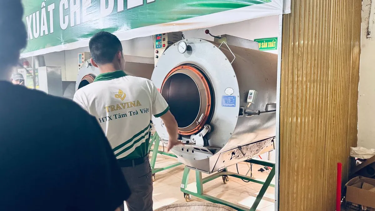 Nhân viên mặc áo TRAVINA thao tác bên máy sao chè lồng quay – TRAVINA HTX Tâm Trà Việt